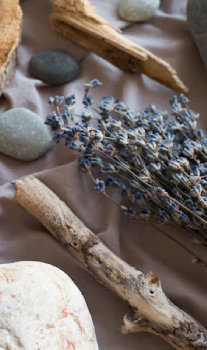 Ramas secas, lavanda y piedras sobre tela beige.